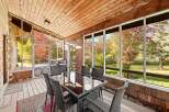 Enjoy the changing seasons from this enclosed sunroom, featuring a dining set perfect for al fresco meals.