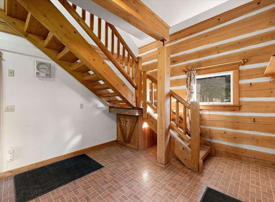 Step into a charming log cabin interior featuring a beautiful wooden staircase that leads to the upper level.