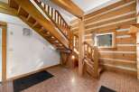 Step into a charming log cabin interior featuring a beautiful wooden staircase that leads to the upper level.