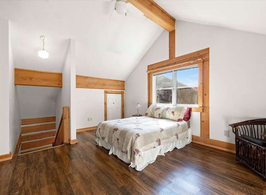 This charming bedroom features a vaulted ceiling with exposed wooden beams, adding a rustic touch.
