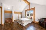This charming bedroom features a vaulted ceiling with exposed wooden beams, adding a rustic touch.