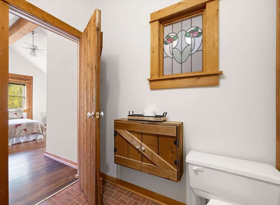 Step into a charming bathroom featuring rustic wooden accents and a beautiful stained-glass window.