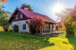 Embrace the charm of autumn with this picturesque home, featuring a vibrant red metal roof and rustic log siding.