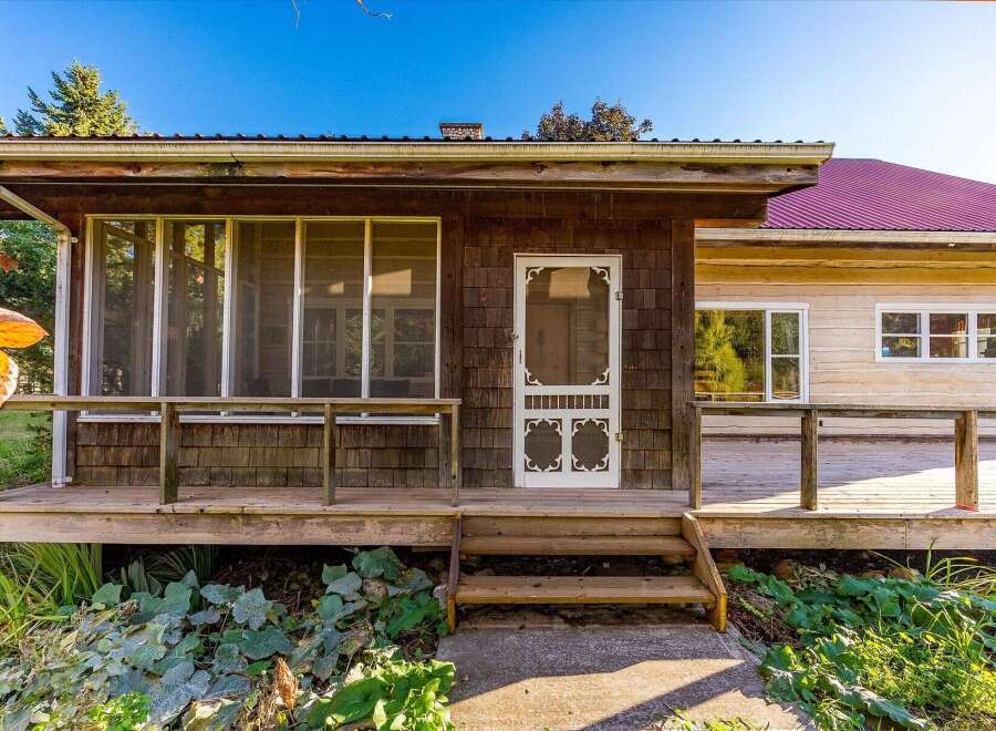 Charming rustic home featuring a welcoming screened-in porch perfect for enjoying the outdoors.