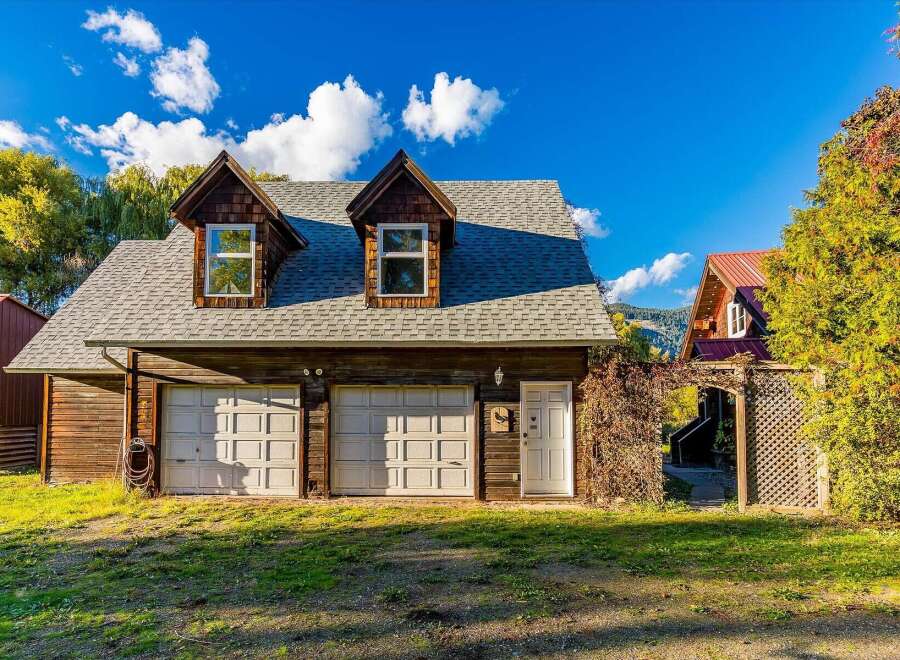 This charming property features a rustic wooden garage with two bays and a separate entrance, perfect for vehicle storage or a workshop.