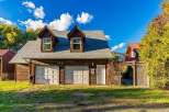 This charming property features a rustic wooden garage with two bays and a separate entrance, perfect for vehicle storage or a workshop.
