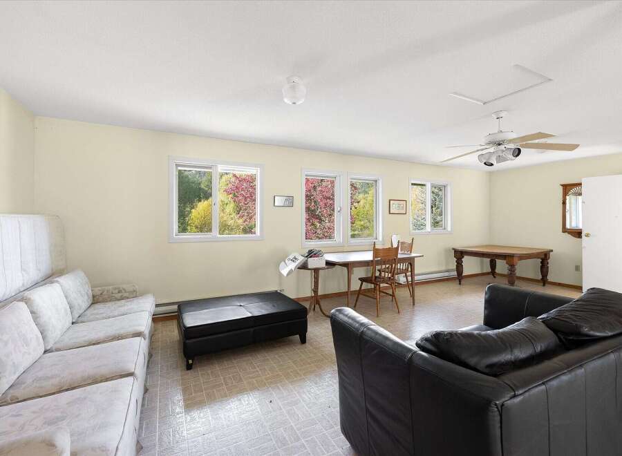 This spacious living area features a comfortable seating arrangement with a white patterned sofa and a black leather couch, perfect for relaxation.