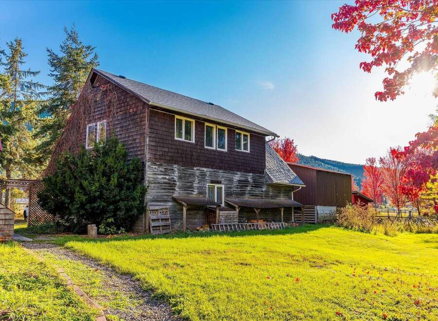 Experience the charm of autumn with this rustic property, featuring a weathered wooden barn and house set against a backdrop of vibrant red maple trees.