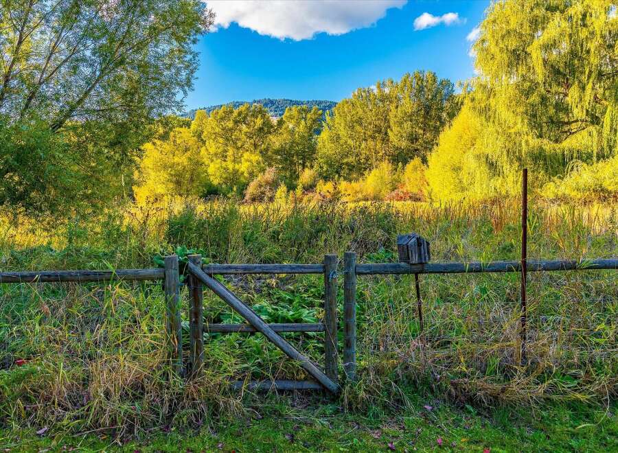 Discover this charming property featuring a rustic wooden fence with a gate, perfect for defining your outdoor space.