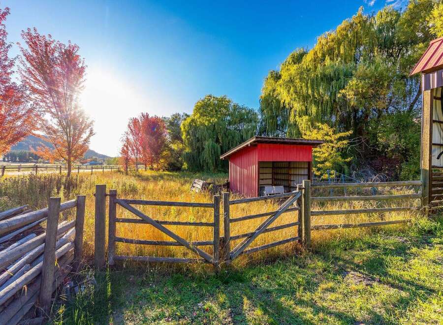 Embrace the charm of autumn on this picturesque property, featuring vibrant fall foliage and a rustic wooden fence.