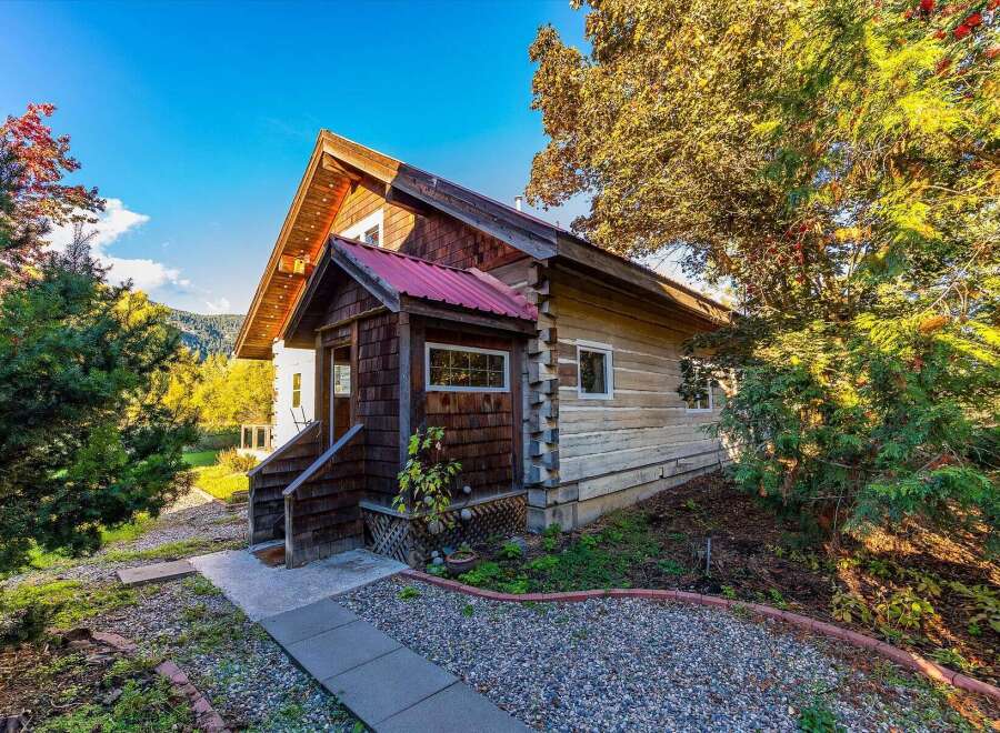 Experience rustic charm in this log cabin featuring a durable red metal roof and natural wood siding.