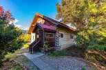Experience rustic charm in this log cabin featuring a durable red metal roof and natural wood siding.