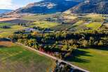 Discover this expansive property, highlighted by a white outline, nestled amidst rolling hills and agricultural fields.
