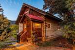 Experience rustic charm in this log cabin home, featuring a vibrant red metal roof and natural wood siding.