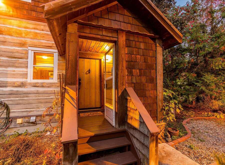 Step into a charming log cabin featuring a welcoming wooden porch with a rustic door and steps.