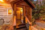 Step into a charming log cabin featuring a welcoming wooden porch with a rustic door and steps.