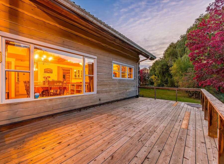 Enjoy the warm glow of this charming log home's interior, visible through its large windows, as dusk settles.