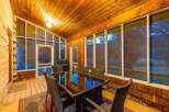 Enjoy outdoor dining and grilling on this charming screened-in porch, complete with a glass-top dining table and chairs.