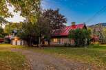 Experience rustic charm in this log cabin home, featuring a vibrant red metal roof and a cozy stone chimney.