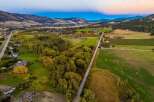 Experience the serene beauty of this rural landscape, featuring a picturesque road winding through lush green fields and vibrant autumn trees.