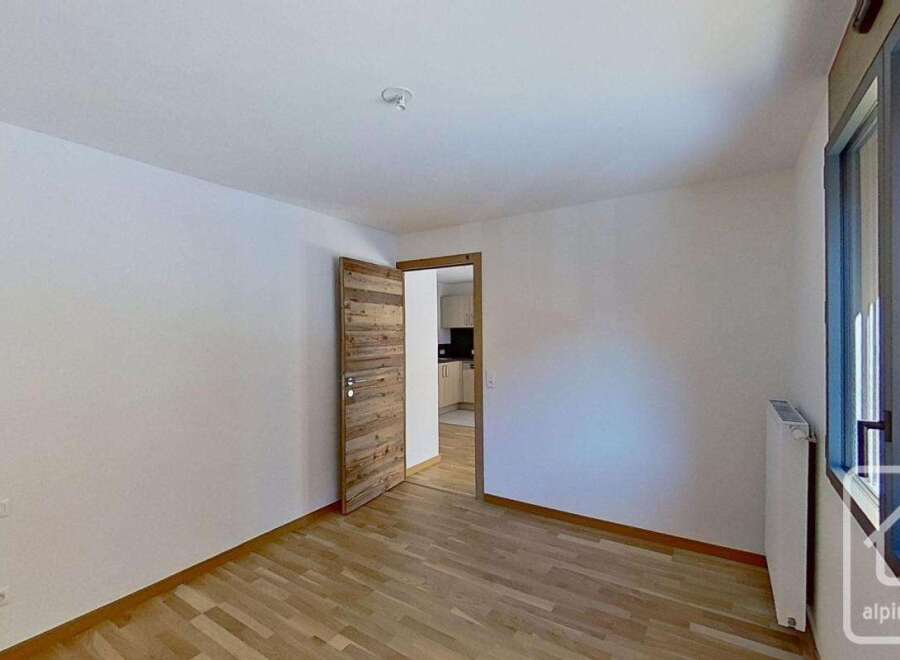 This spacious room features a modern wooden door leading to an adjacent kitchen area.