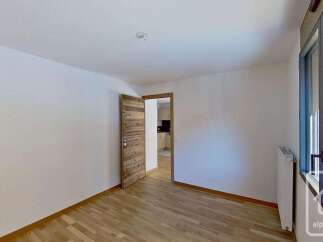 This spacious room features a modern wooden door leading to an adjacent kitchen area.
