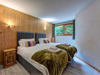 Experience cozy comfort in this charming bedroom featuring two twin beds, perfect for families or friends.