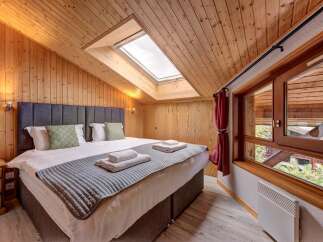 Experience cozy comfort in this charming bedroom, featuring a plush king-sized bed adorned with crisp white linens and decorative pillows.