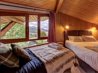 Experience cozy mountain living in this charming bedroom featuring a vaulted wooden ceiling and paneled walls.