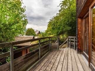 Enjoy the outdoors from this charming wooden deck, offering a rustic ambiance surrounded by lush greenery.