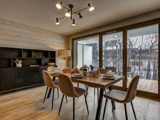 Experience modern living in this beautifully appointed dining area, featuring a rustic wooden dining table set for a meal and surrounded by plush, upholstered chairs.