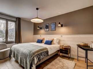 Experience cozy mountain living in this charming bedroom, featuring a comfortable bed adorned with plush pillows and a warm, textured throw blanket.