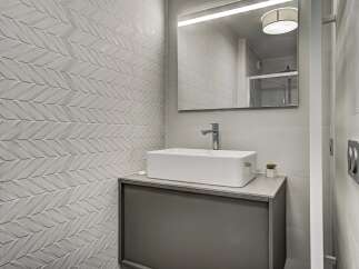 This modern bathroom features a striking textured tile wall with a chevron pattern, adding depth and visual interest.