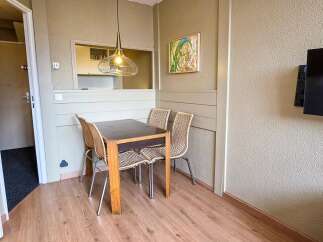 This dining area features a modern glass pendant light hanging over a dark-topped wooden table with four woven chairs.