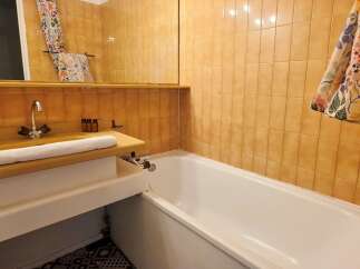 This bathroom features a bright and airy design with warm, orange tiled walls and a spacious white bathtub.
