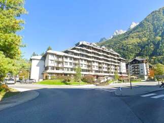 Discover this stunning multi-story apartment building nestled against a backdrop of majestic mountains.