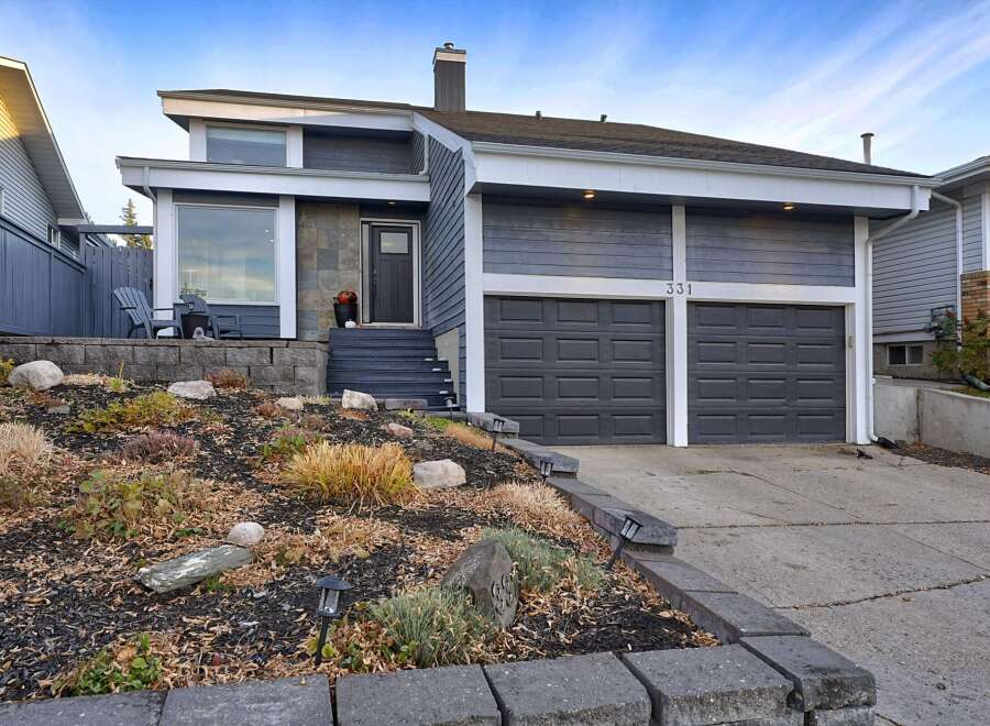 This modern home features a striking dark gray exterior with contrasting white trim and a stone-accented entryway.