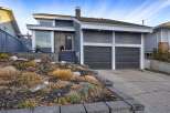 This modern home features a striking dark gray exterior with contrasting white trim and a stone-accented entryway.