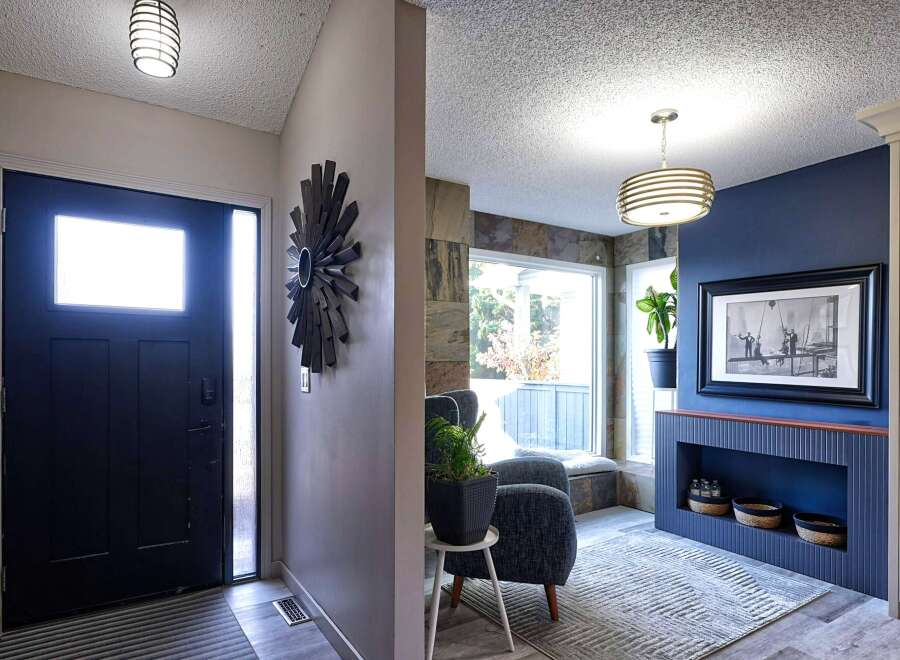 Step into a welcoming entryway featuring a sleek black door with a frosted glass panel, complemented by a modern spiral light fixture.
