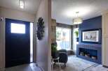 Step into a welcoming entryway featuring a sleek black door with a frosted glass panel, complemented by a modern spiral light fixture.