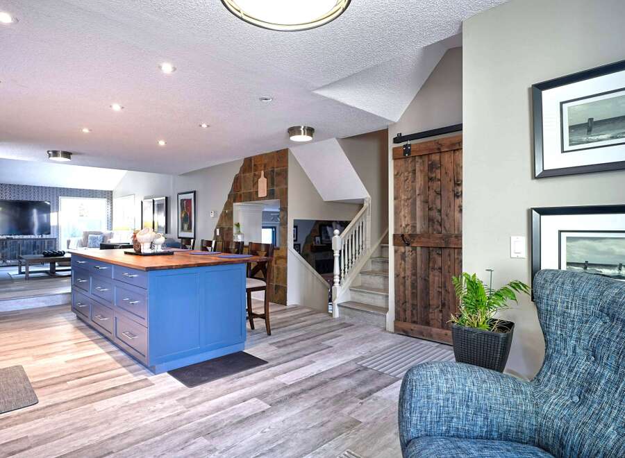 This open-concept living space features a vibrant blue kitchen island with a butcher block countertop, perfect for meal prep and casual dining.