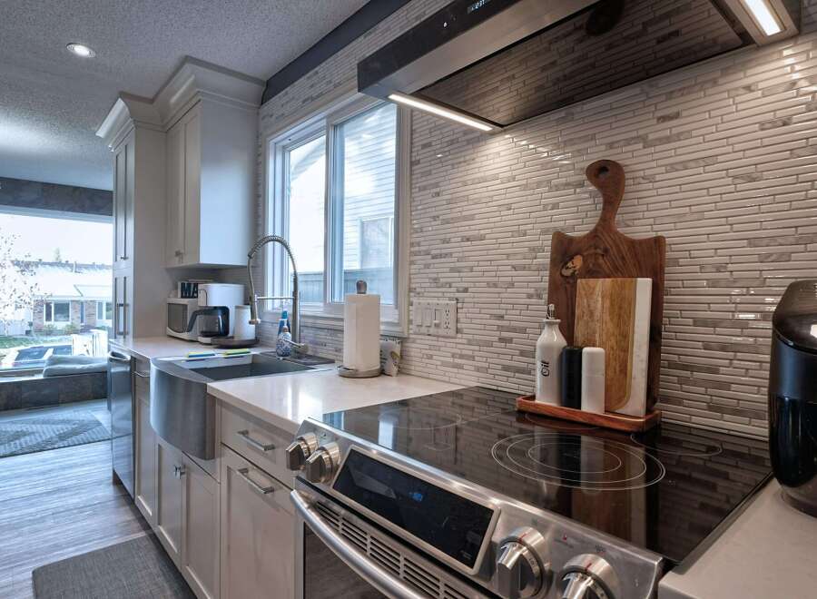 Experience the heart of this home with a beautifully updated kitchen, featuring sleek white cabinetry and a stunning mosaic tile backsplash.