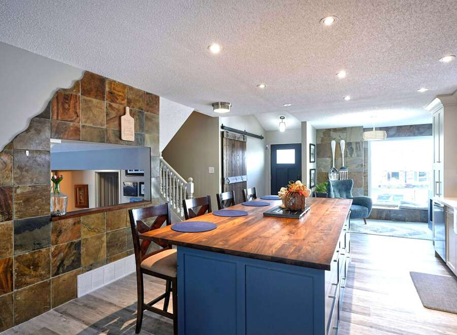 This open-concept living space boasts a stunning slate tile accent wall that adds a rustic charm to the modern design.