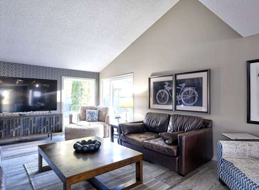 Step into this inviting living room featuring a vaulted ceiling and a large flat-screen TV mounted above a stylish, modern media console.