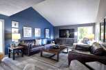 Experience modern living in this stunning living room, featuring a vaulted ceiling and a dramatic navy blue accent wall.