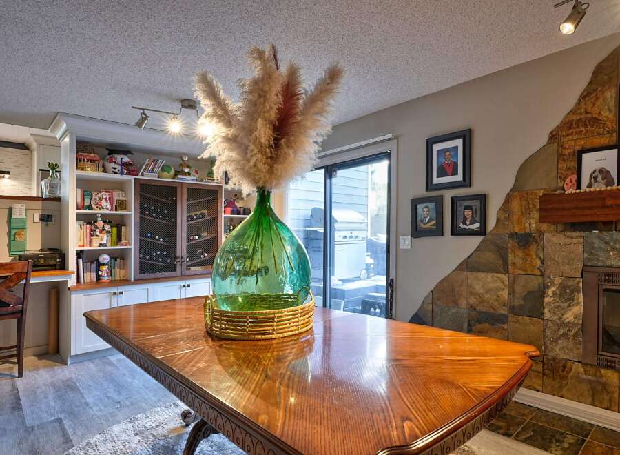 This dining area features a large wooden table, perfect for family gatherings, complemented by a striking green glass vase filled with pampas grass.