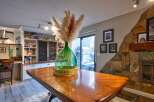 This dining area features a large wooden table, perfect for family gatherings, complemented by a striking green glass vase filled with pampas grass.