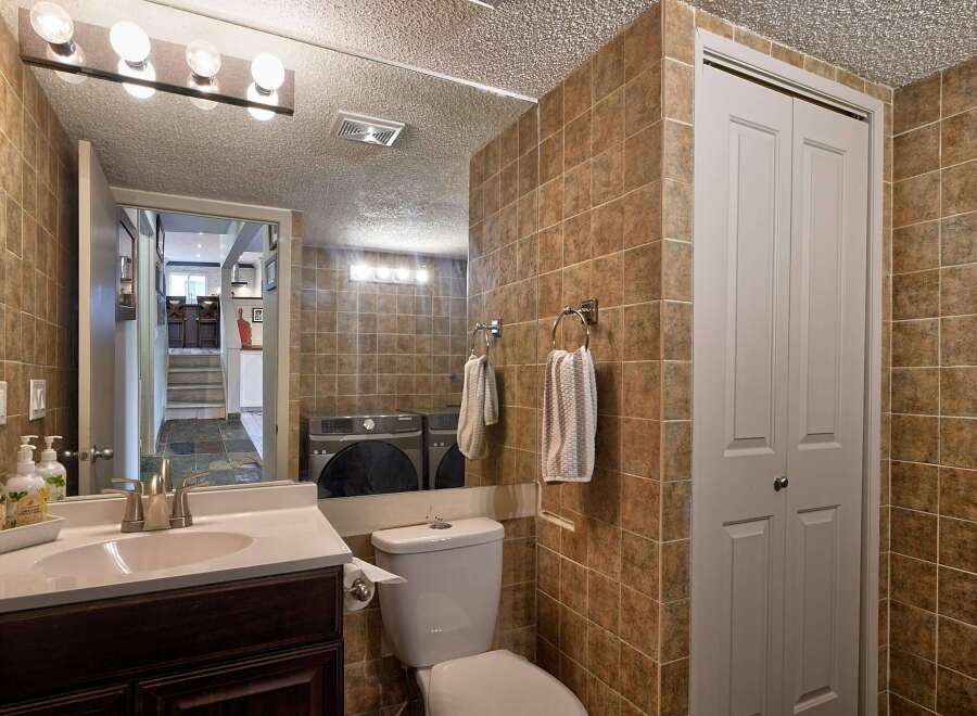 This bathroom features a modern vanity with a sleek faucet and a white sink, complemented by warm-toned tiled walls.