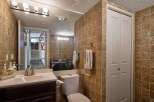This bathroom features a modern vanity with a sleek faucet and a white sink, complemented by warm-toned tiled walls.