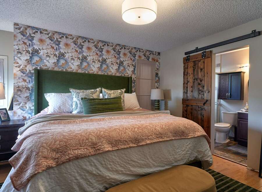 Experience comfort and style in this beautifully appointed bedroom, featuring a striking floral wallpaper accent wall that adds a touch of elegance.
